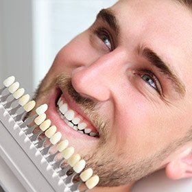man comparing teeth to whitening chart