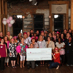 group smiling with giant check