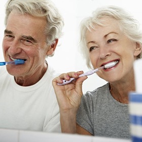 senior man and woman brushing their teeth 