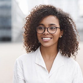 Woman with glasses standing outside and smiling