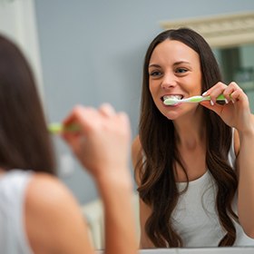 Woman looking in mirror and brushing her teeth