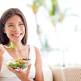 Woman sitting on couch and eating a salad
