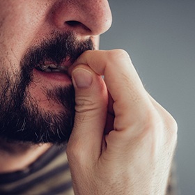 Man with beard biting his fingernails