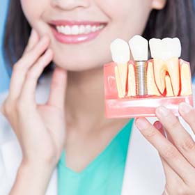 dentist holding a model of a dental implant in the jaw