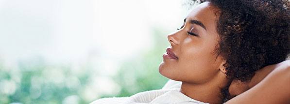 Woman lying down with eyes closed and hands behind her head