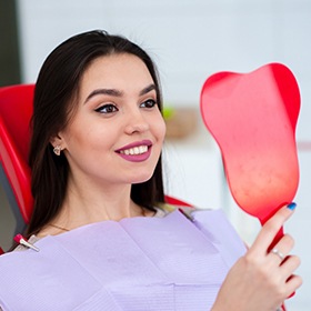 woman smiling into red mirror