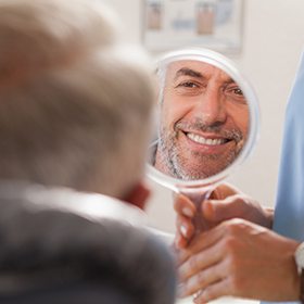 man smiling in white round mirror