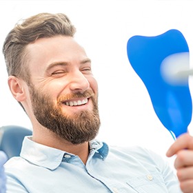 man smiling into bright blue mirror