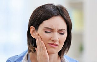 woman holding jaw in pain