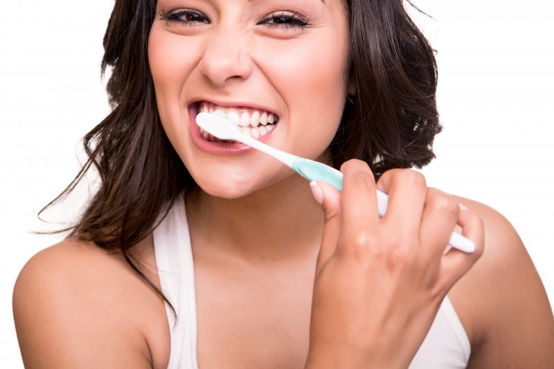 attractive woman brushing her teeth before visiting dentist in Lawrenceville