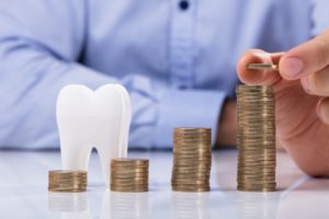 piles of coins for dental implants in Lawrenceville and model tooth