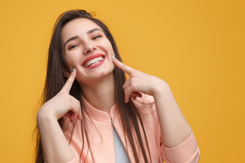 girl smiling and pointing to her smile