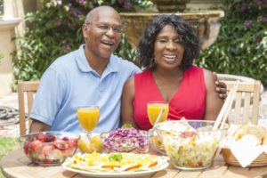 senior man and woman eating summer foods with dental implants 