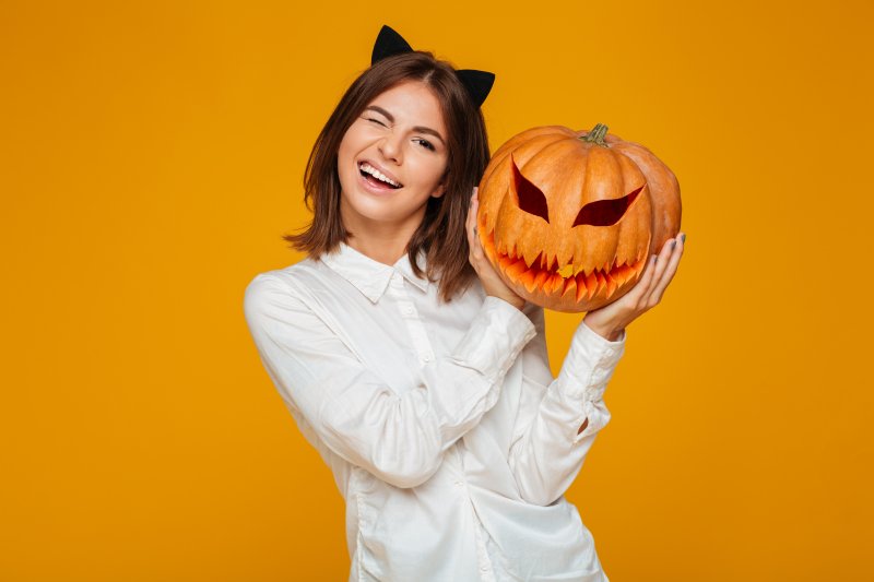 Smiling woman holding a pumpkin and winking