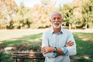 Senior man with dental implants outside smiling