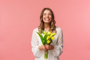 a woman smiling and holding spring flowers