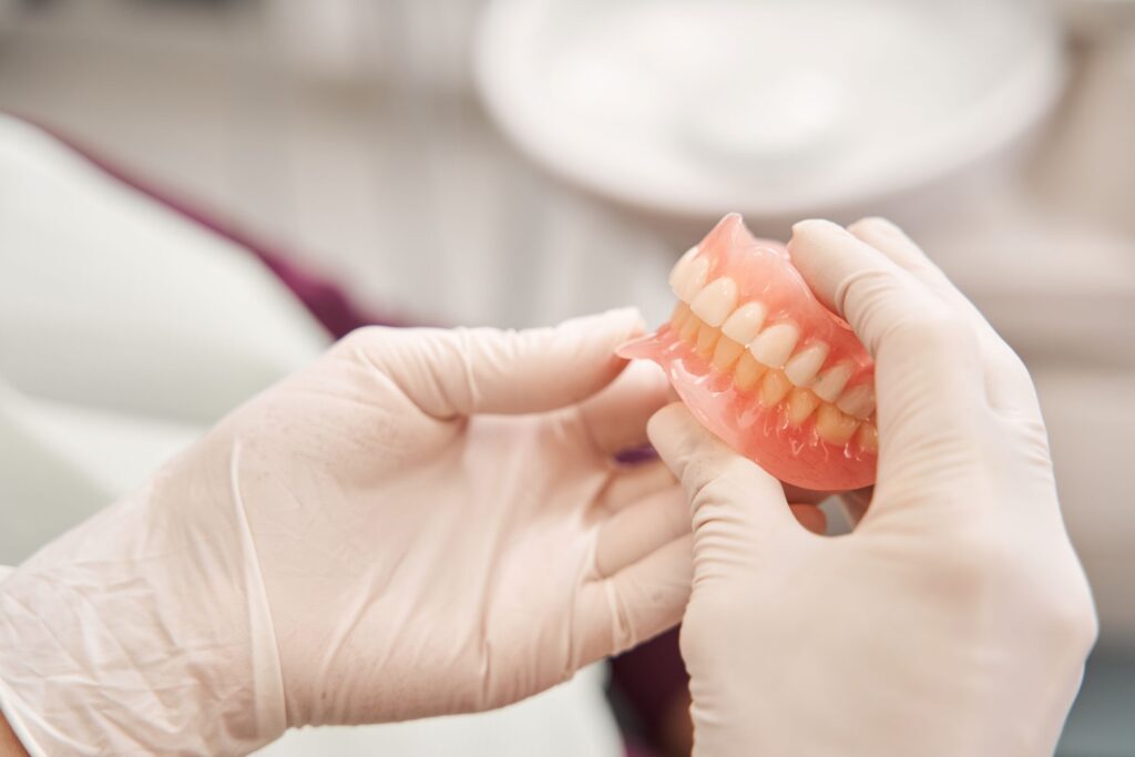 Dentist in white gloves holding complete set of dentures